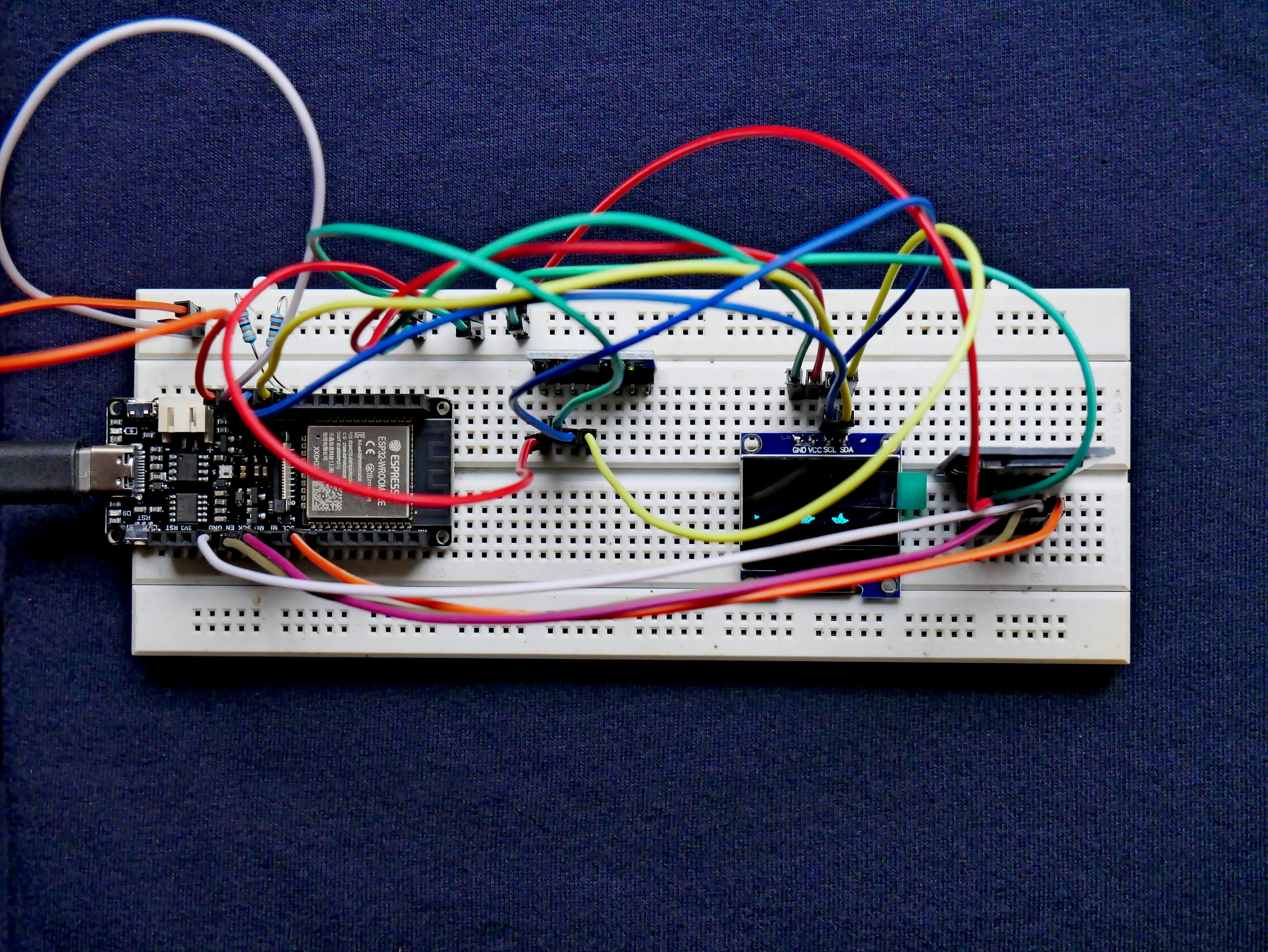 A development board, sensor, and small display connected on a breadboard.