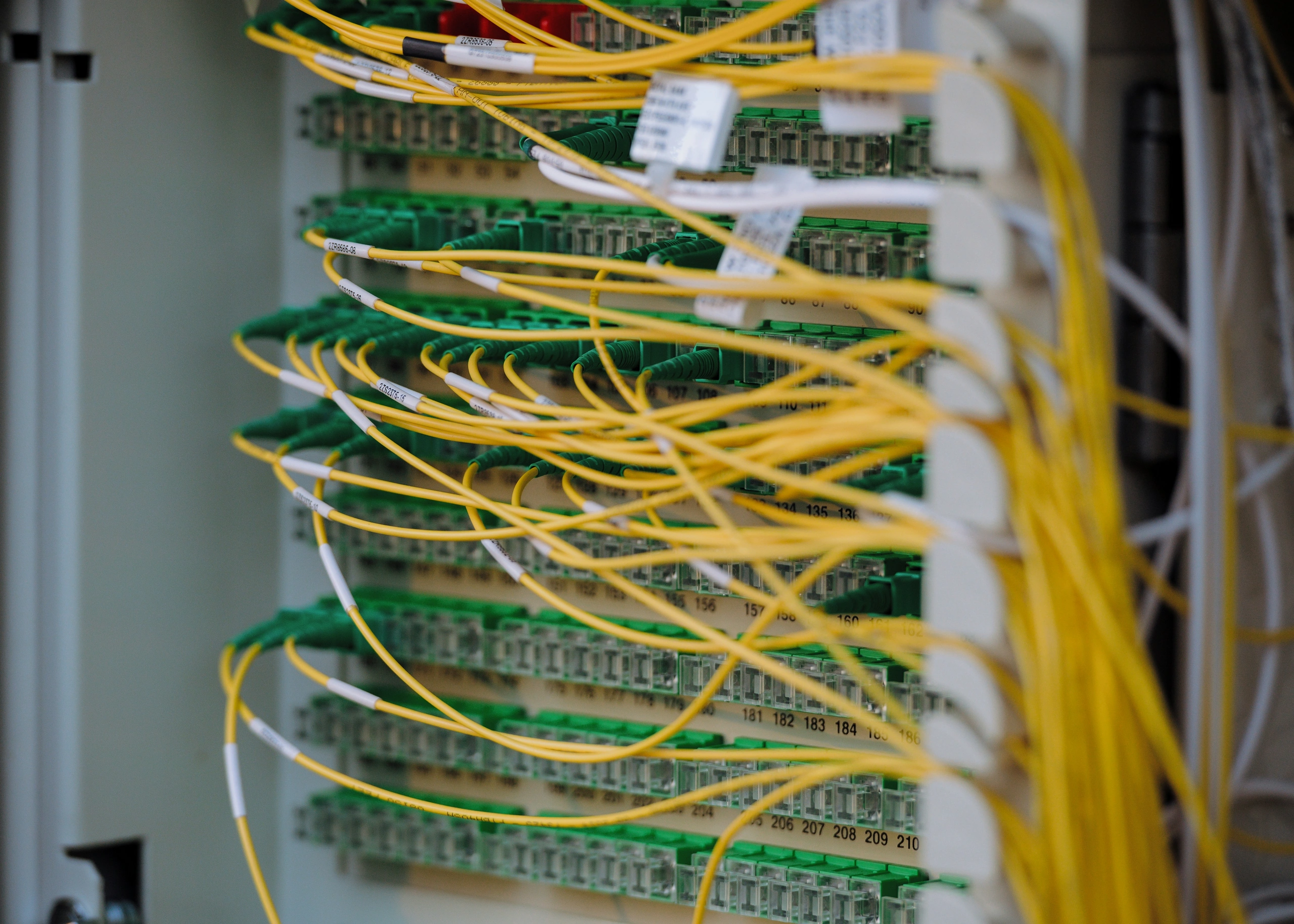 Yellow fiber-optic cables connected to green network ports.